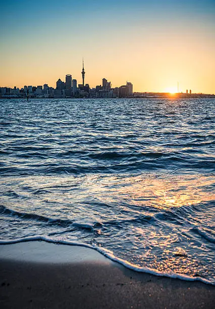 Auckland's CBD silhouetted against a setting sun, photographed from the Devonport beach.