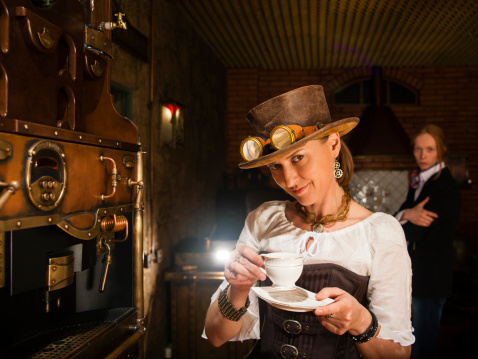 Young woman in steampunk stile make a coffee with coffee-macker machine