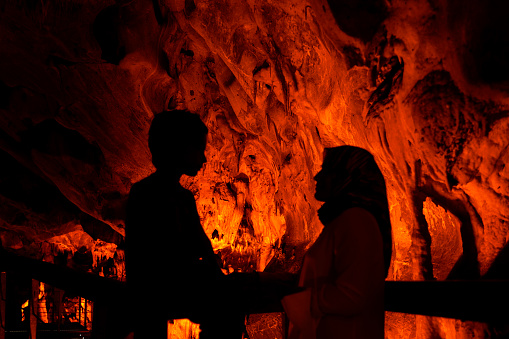 The mother takes her son around the cave and they explore and learn together.. Natural formations are visible in the illuminated cave. Abstract shapes were formed with the effects of shadow and light. Shot with a full frame camera.