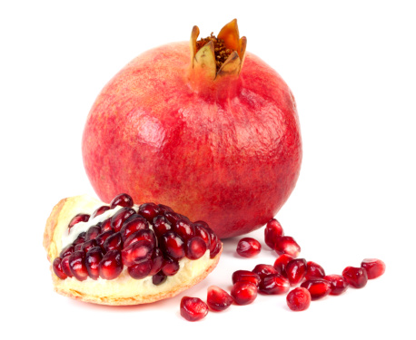 Image of Still Life with Turkish Pomegranate and olive branch on old retro plate. Dark wood background, antique copper plate. Fresh ripe whole pomegranates, opened pomegranate and seeds