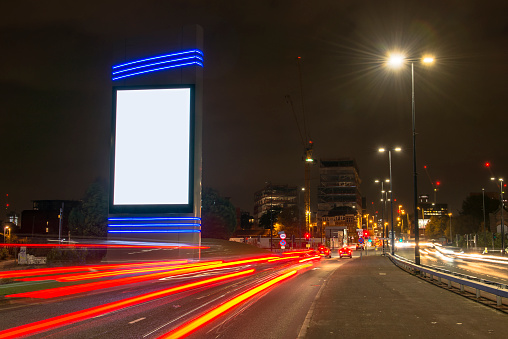 A digital out of home media billboard at night with traffic light streaks