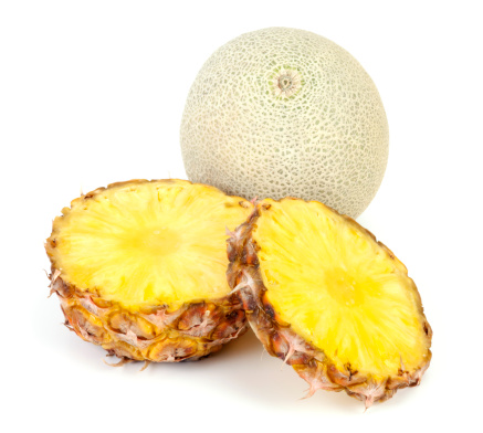 Slices of Pineapple and whole cantaloupe on white background. Selective focus and shallow DOF.