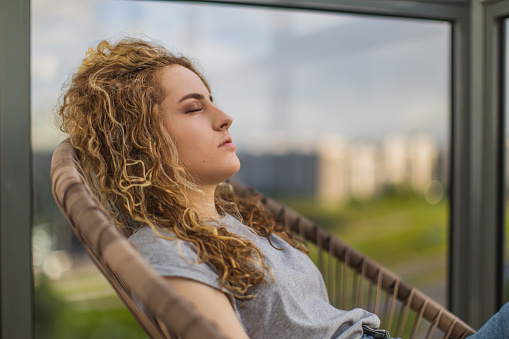 Curly redhead woman sleeping in chair on balcony.