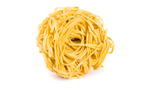 uncooked pasta nest on white background