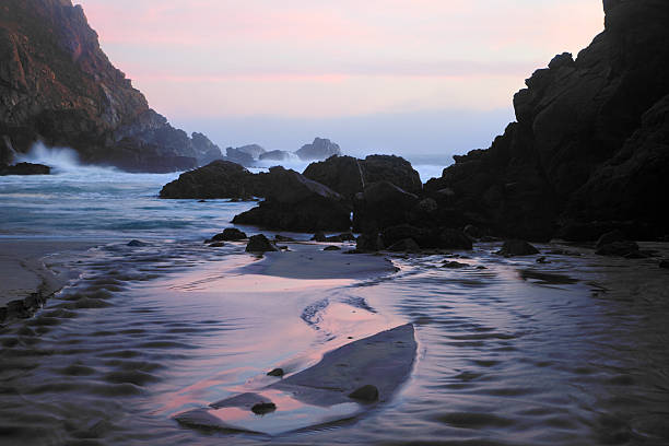 Pfeiffer Beach Rocks, Purple Sand and Sunset Low tide sunset on Pfeiffer Beach on California's Central Coast. The sand there is purple; add a pink sunset and you get a very cool-toned scene. A stream feeds in from the lower left (which is where the pink sand comes from - it is manganese garnet washed out of the surrounding mountains). terryfic3d stock pictures, royalty-free photos & images