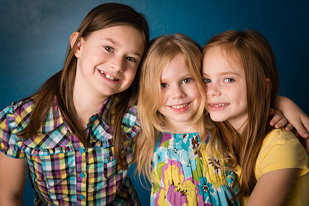 three sisters juntos, em pé e abraçando no interior - embracing smiling gap children only - fotografias e filmes do acervo