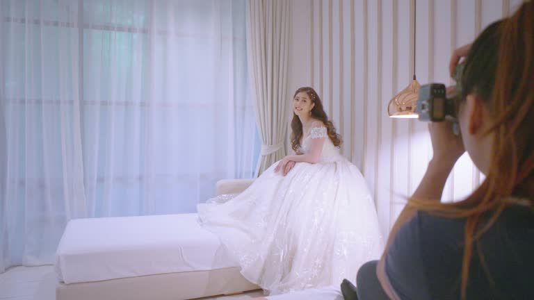 Photographer is taking a photo of the bride while she is sitting on the sofa in the hotel room.