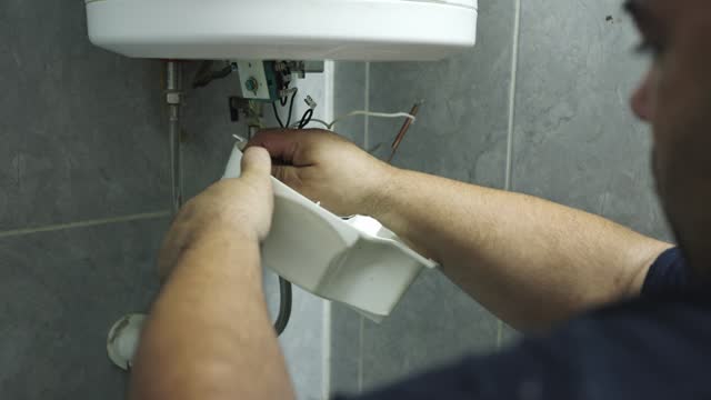 B-roll of an Caucasian male heating engineer repairing a boiler at the customer domestic bathroom