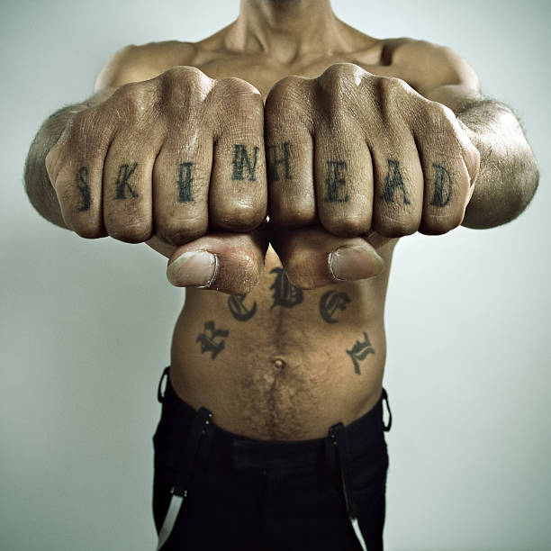 Skinhead Showing off Knuckle tattoo Antiracist original black skinhead showing his tattoos. skin head stock pictures, royalty-free photos & images