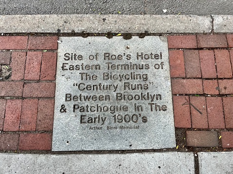 Patchogue, NY, USA, 7.21.23 - The top down view of a cement tile on a sidewalk that is engraved with a historical marker.  It notes the \