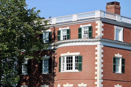 Boston, MA, USA-September 2022; Low angle partial view of Johnston Gate in Georgian Revival design which is the main entrance to the Harvard Yard of Harvard University and roof of building in back