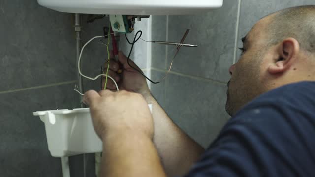 B-roll of an Caucasian male handyman repairing a boiler at the customer domestic bathroom