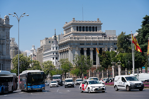 Taxi, buses and small cars go through traffic on Alcala street with the Cervantes street in the background. Madrid. Spain. July 27, 2023.