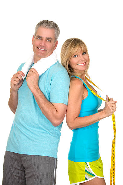 Couple standing back to back in workout gear mature couple in sports wear as health fitness and weight loss concept exercising tape measure women healthy lifestyle stock pictures, royalty-free photos & images