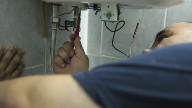 Caucasian male handyman repair a boiler at the customer domestic bathroom