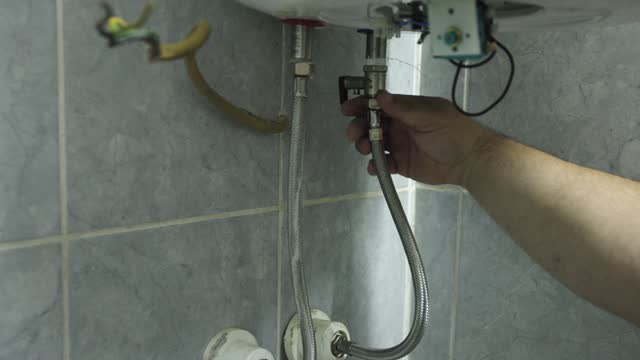 Caucasian male heating engineer repair a boiler at the customer domestic bathroom