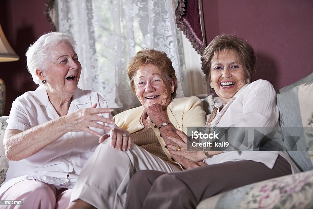 Elderly women on living room sofa Group of senior women (80s) laughing together on living room couch. Senior Adult Stock Photo