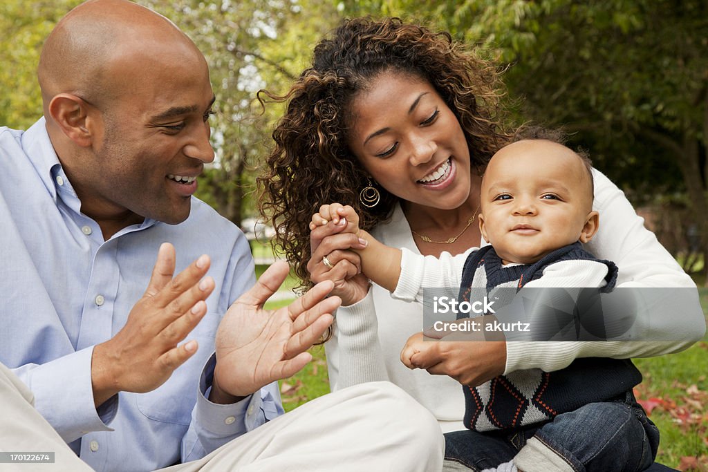 Mãe e pai brincando com seu bebê menino no parque - Foto de stock de Movimento royalty-free