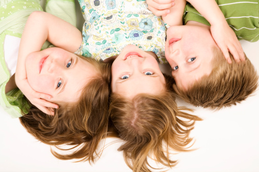 Three adorable children blond elementary age indoors blue eyes white