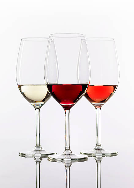 three wineglasses with wine three wineglasses with white wine, rose wine and red wine on white background with reflection winetasting rose wine wineglass elegance stock pictures, royalty-free photos & images