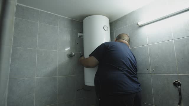 Caucasian male heating engineer adjusting the boiler at the clients bathroom