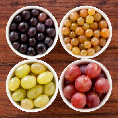 Four bowls containing different types of grapes