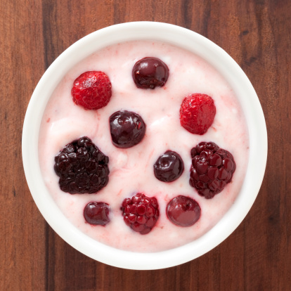 Top view of white bowl full of yogurt with variety of berries (raspberries, blueberries and blackberries)