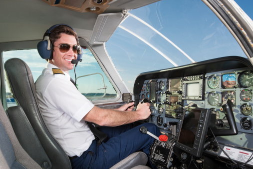 A pilot in the cockpit of a small commuter airplane.