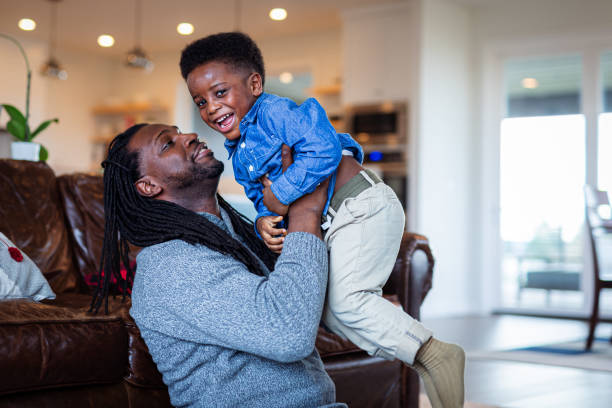 istock Father playfully lifts young son in air while bonding at home 1701294832