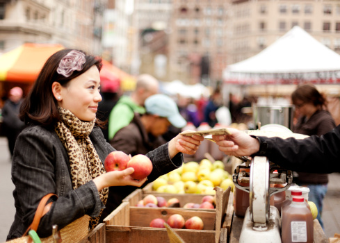 A young Chinese woman buying apples in a fruit and vegetable market, New York City
