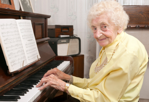 An elderly lady playing her piano.