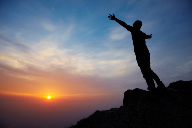 istock young man on the mountain top with sunrise 170132234