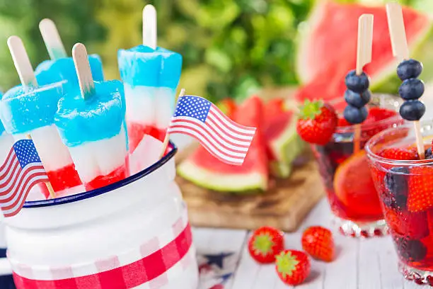 Homemade red-white-and-blue popsicles on an outdoor table.