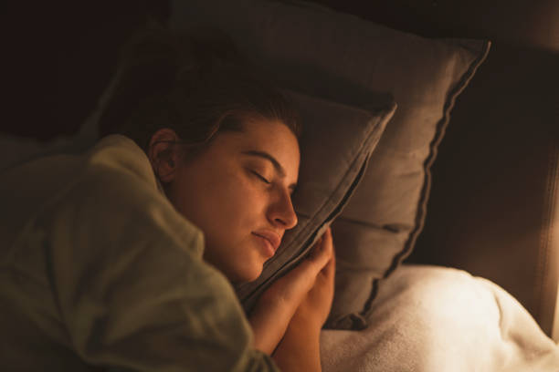 Lamp illuminating sleeping young woman.