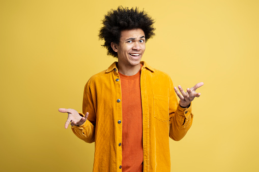 Pensive African American man dont understand, looking for creative solution isolated on yellow background. Portrait of young serious university student looking at camera, thinking. Education concept