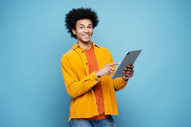 istock Smiling African American man holding digital tablet isolated on blue background 1701339498