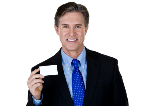 Man wearing a suit and tie and holding a blank business card while being isolated on a white background 