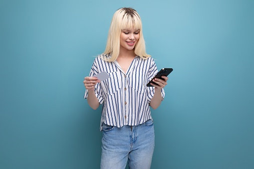 blond 25 year old woman person in a striped blouse and jeans holds a map and smartphone/