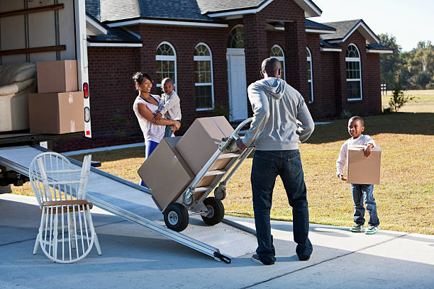 African American family moving house African American family moving house.  Main focus on man and little boy carrying box. moving van stock pictures, royalty-free photos & images