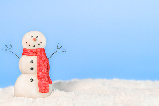 Happy Snowman in the snow. Blue snowy background with copy space. Can be used as holiday greeting card for Christmas and New year, postcard, advertising, marketing, invitations, winter storytelling. Majestic. Not AI.