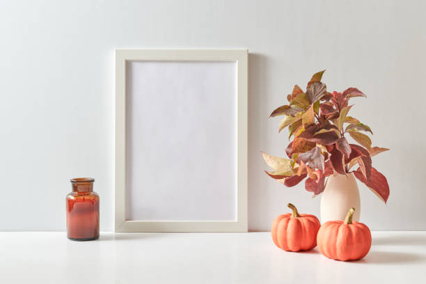 istock Mockup with a white frame and colorful autumn leaves in a vase on a light background. Empty poster frame mockup for presentation design, text, lettering 1701408488
