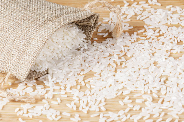 istock Burlap Sack of White Rice spilling out onto cutting board 1701430722