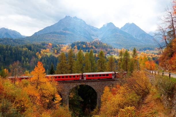 istock A train  travels on a bridge thru fall colors and Tarasp Castle perches on a hill under alpine mountains in background, in Scuol, Engadin Valley, Grisons (Graubünden), Switzerland 1701437336