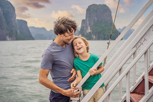 Father and son travelers is traveling by boat in Halong Bay. Vietnam. Travel to Asia, happiness emotion, summer holiday concept. Traveling with children concept. After COVID 19. Picturesque sea landscape. Ha Long Bay, Vietnam.