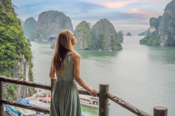 Attractive woman in a dress is traveling in Halong Bay. Vietnam. Travel to Asia, happiness emotion, summer holiday concept. Picturesque sea landscape. Ha Long Bay, Vietnam stock photo