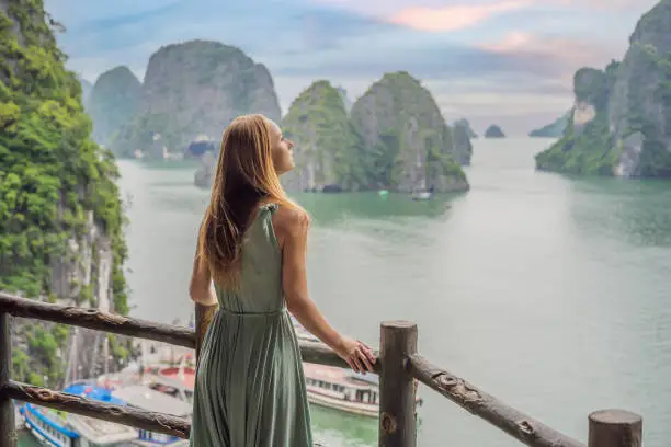 Attractive woman in a dress is traveling in Halong Bay. Vietnam. Travel to Asia, happiness emotion, summer holiday concept. Picturesque sea landscape. Ha Long Bay, Vietnam.