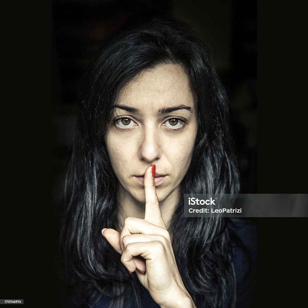 Serious woman, finger on lips Serious woman portrait on black background. Finger on Lips Stock Photo