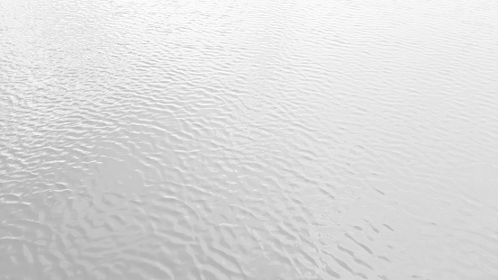 white colored clear calm water surface texture. lake water background. gentle waves in white color tone. white lake water background texture with blank space for design.