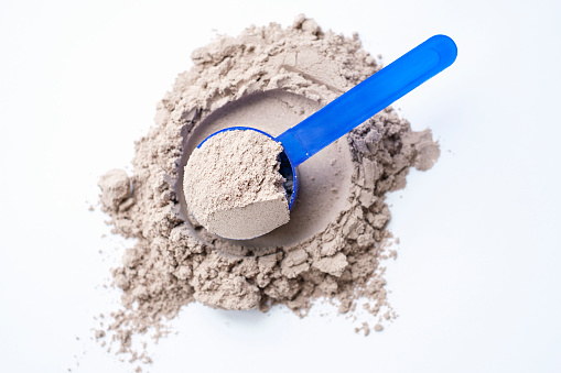 istock Scattered brown protein and scoop on white background top view. 1701472845