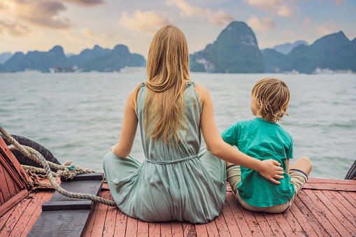 Mom and son travelers is traveling by boat in Halong Bay. Vietnam. Travel to Asia, happiness emotion, summer holiday concept. Traveling with children concept. After COVID 19. Picturesque sea landscape. Ha Long Bay, Vietnam.